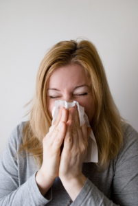 Woman sneezing with tissue