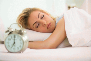 Woman sleeping with alarm clock showing 7:00 AM