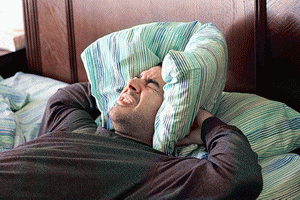 Man-having-trouble-sleeping-squeezes-a-pillow-around-his-ears