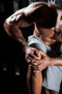 Portrait of a muscle fitness man reaching for his knee 