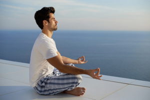 Man practicing yoga on the beach