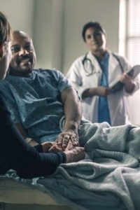 a-male-patient-smiles-while-holding-the-hand-of-a-friend