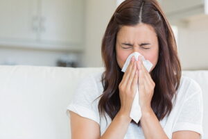 Girl sneezing in a tissue in the living room