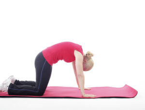 Woman doing a cat or camel stretch with an arched back