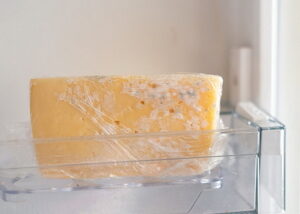 Moldy cheese wrapped in cling film in the refrigerator